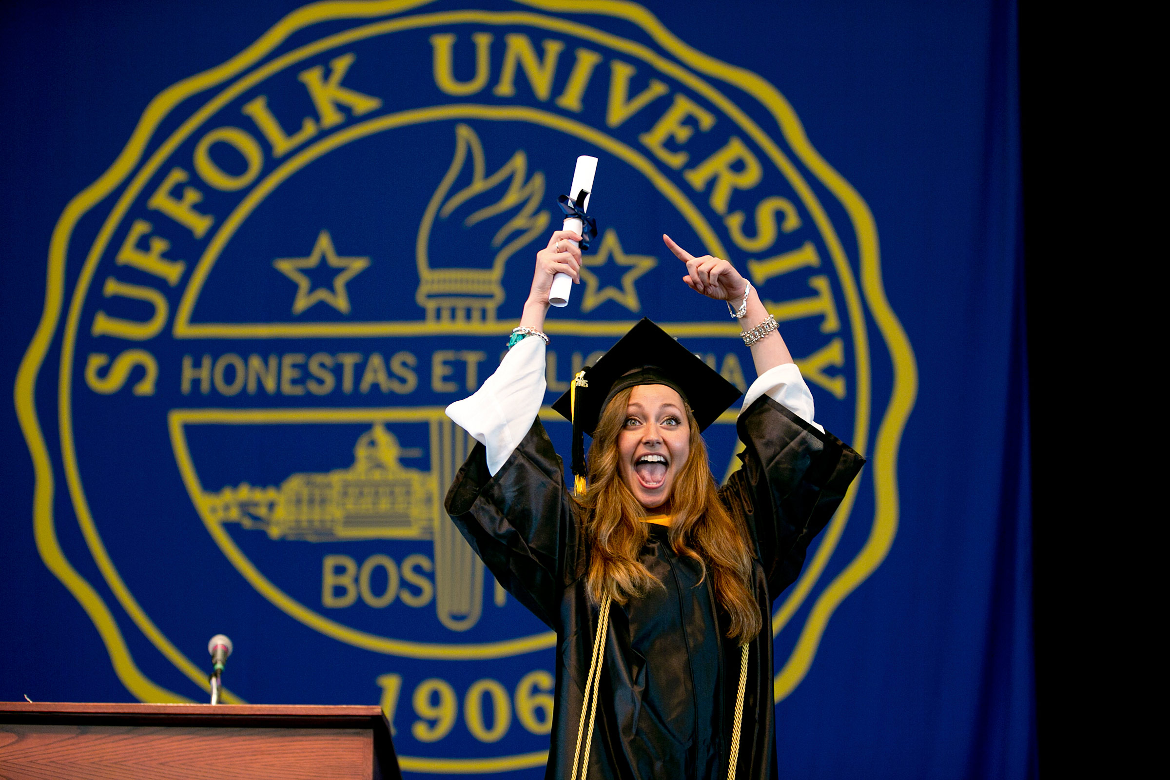 A jubilant Suffolk University graduate holds her diploma for family to see.