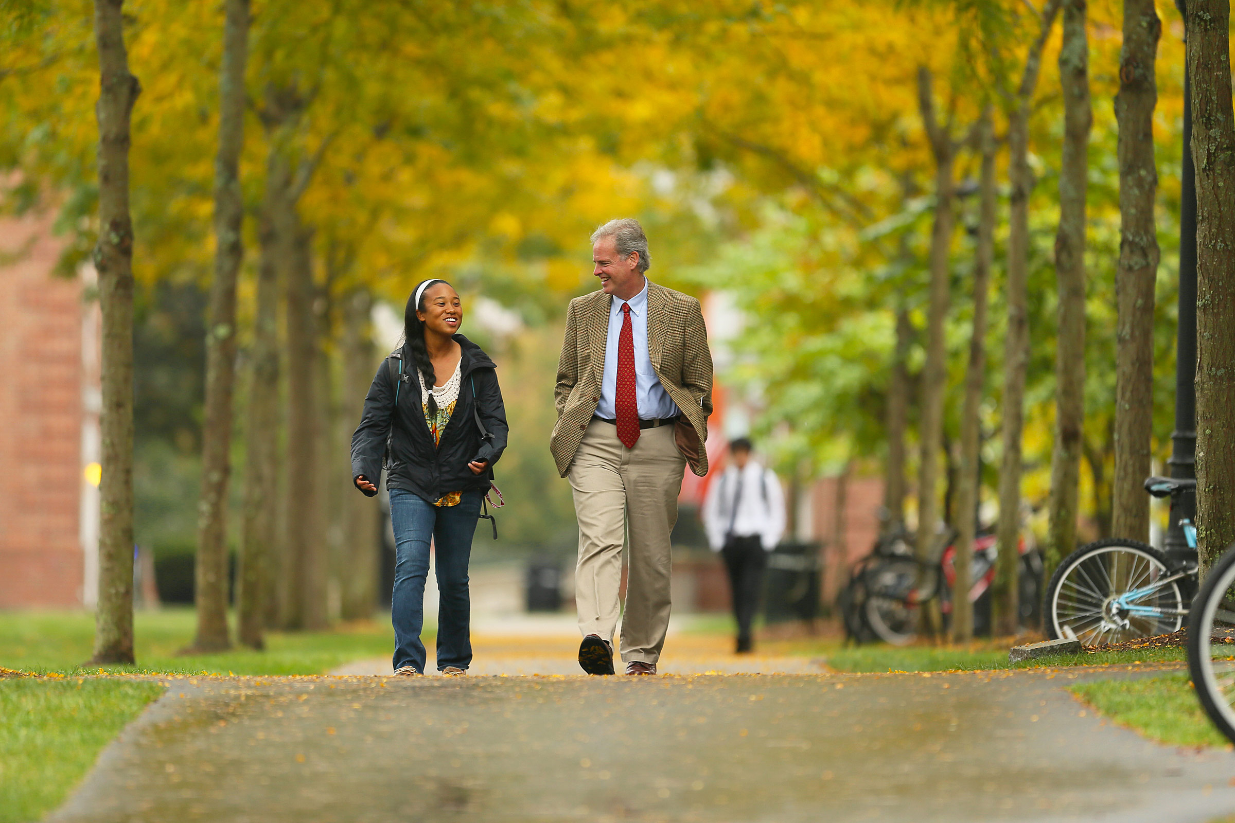 Fall colors are out as Phillips Exeter principal Thomas Hassan walks with a student.