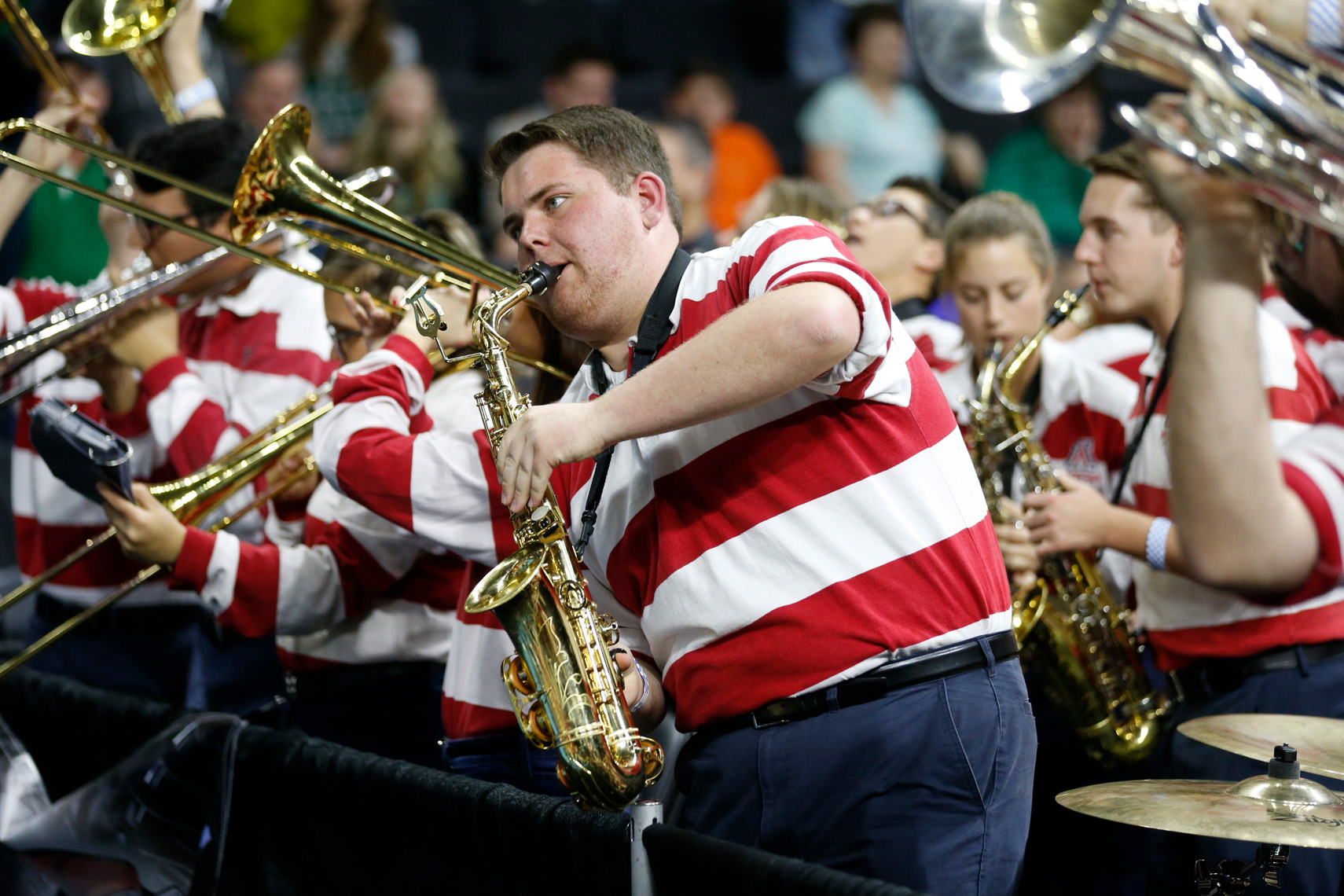 A  striped shirt saxophone player leads the  Arizona pep band during a NCAA game.
