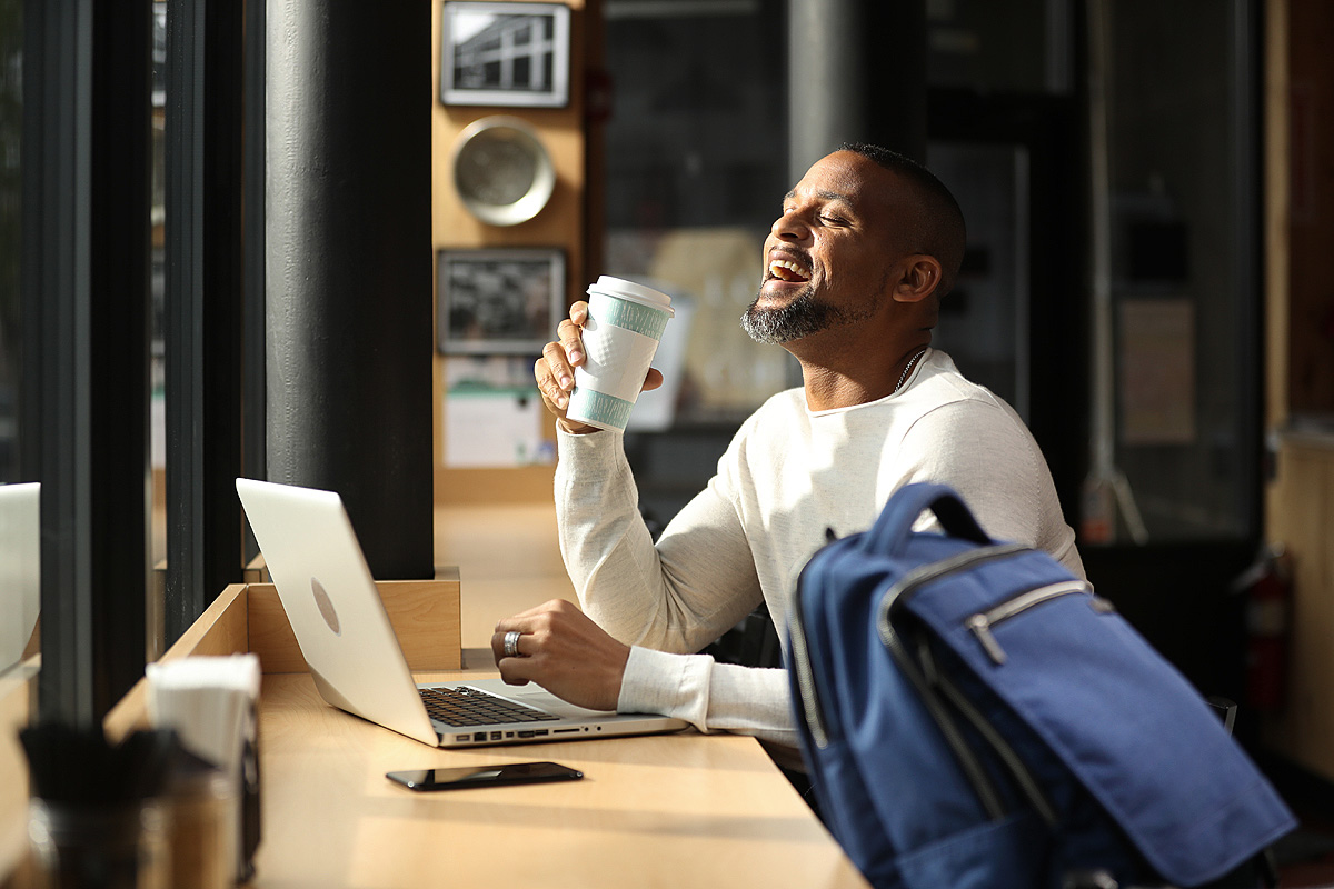 Fitness guru Shaun T enjoys a cup of coffee in a light bathed coffee shop.
