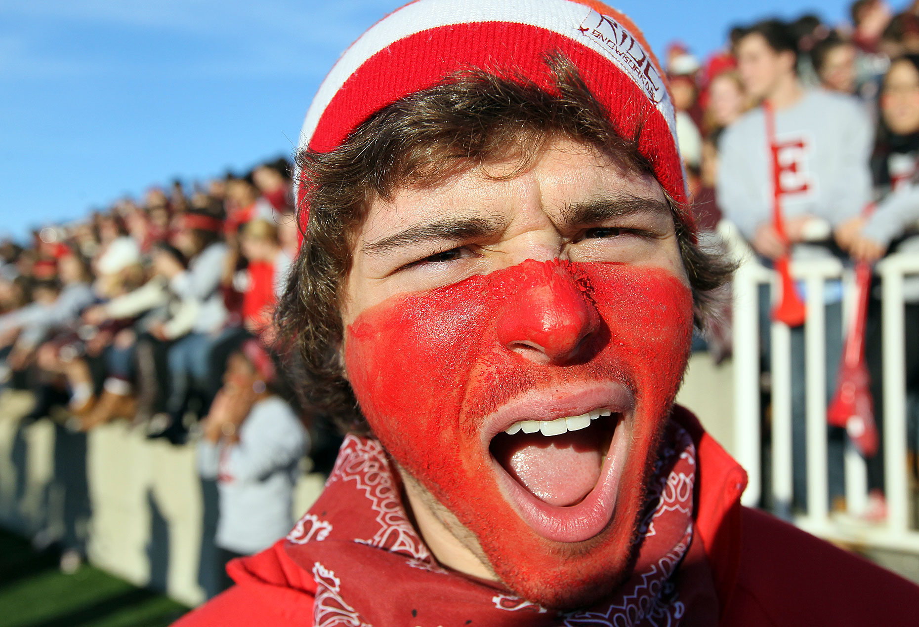 A Phillips Exeter student with a red painted face cheers for his team in a game.